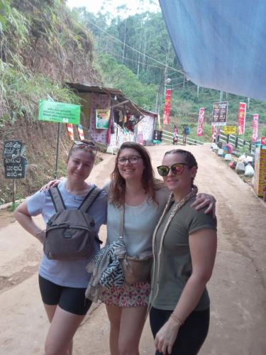 three women standing next to each other on a dirt road at Trinish homestay in Hatton