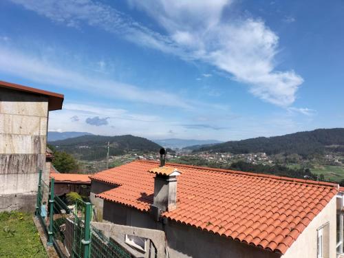 ein Gebäude mit einem orangefarbenen Kacheldach mit Bergen im Hintergrund in der Unterkunft Apartamento Portocelo, en Marín (Pontevedra) in Marín