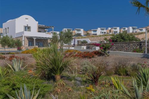 a garden in front of a white building at Desiterra Resort & Spa in Fira
