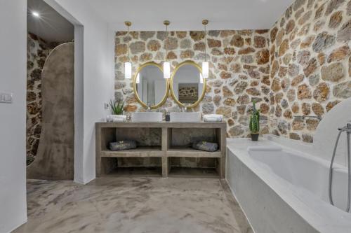 a bathroom with two sinks and a tub and a mirror at Desiterra Resort & Spa in Fira