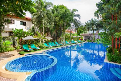 a pool at a resort with blue chairs and palm trees at Thanthip Beach Resort - SHA Extra Plus in Patong Beach