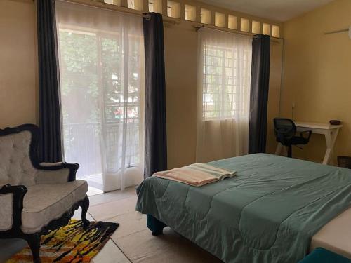 a bedroom with a bed and a chair and a window at Tudor Court 2 in Mombasa