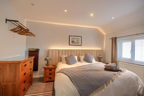 a bedroom with a bed and a dresser and a window at Smugglers Luxury Accommodation in Sheringham