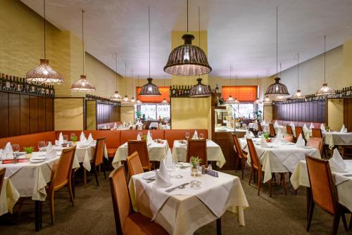 un restaurante con mesas blancas, sillas y luces en Graben Hotel, en Viena