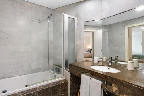 a bathroom with a sink and a tub and a mirror at Forum T0 Plus in Ilhéu do Gorgulho
