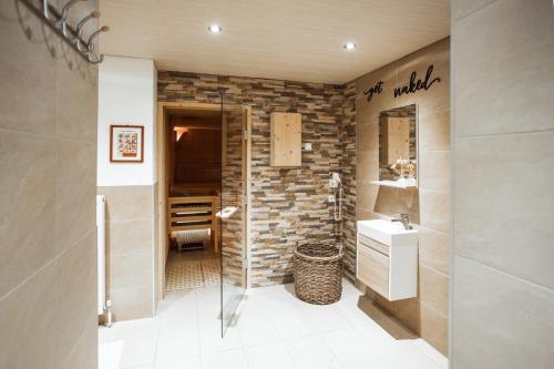 a bathroom with a walk in shower and a sink at Pension Eschenhof in Kaprun