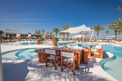 un complejo con piscina con mesa y sillas en Nikki Beach Resort & Spa Dubai, en Dubái