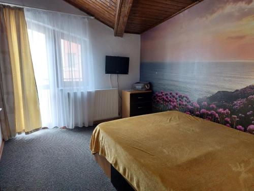 een slaapkamer met een schilderij van bloemen aan de muur bij Vila Foc Alb Apartamente-Busteni in Buşteni