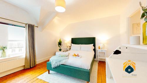 a bedroom with a bed and a green chair at Large 2-Bed City Apartment in Cardiff in Cardiff