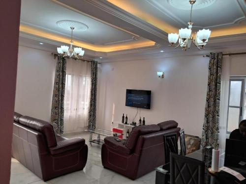 uma sala de estar com duas cadeiras e uma televisão em Residence New Standing Douala CITE CHIRAC YASSA em Douala