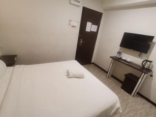 a hotel room with a white bed and a flat screen tv at Grand Kapar Hotel Kuala Selangor in Kuala Selangor