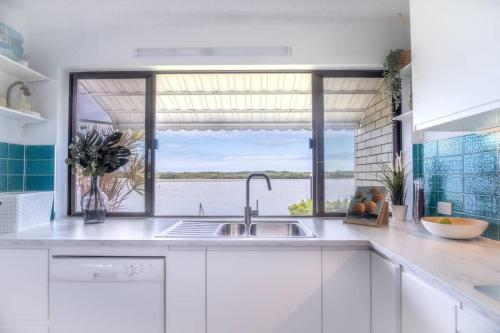 a kitchen with a sink and a large window at Peaceful River Front Escape Short walk to Ocean St in Maroochydore