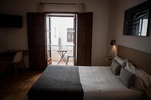 een slaapkamer met een bed en uitzicht op een balkon bij Hostal Café FRENTEABASTOS in Carmona