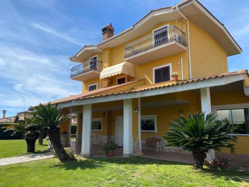 a yellow house with palm trees in front of it at Relais Le Folaghe in Ladispoli