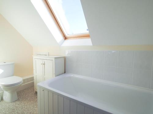 a white bathroom with a toilet and a skylight at Golygfa Mor Tresaith 
