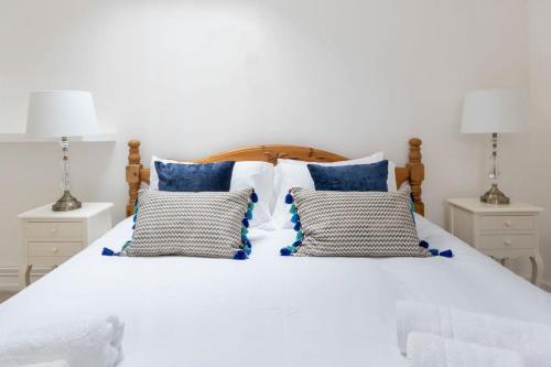 a white bed with blue pillows and two lamps at Independence House in Oakham