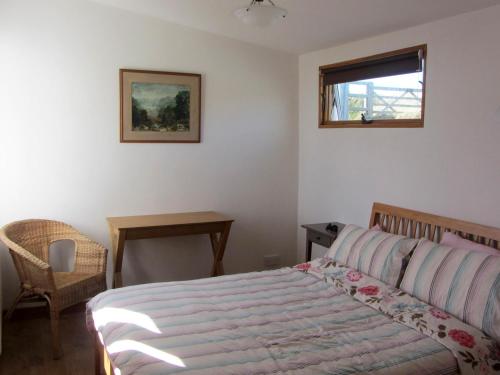 a bedroom with a bed and a table and a window at Rockfield Broad Haven in Broad Haven