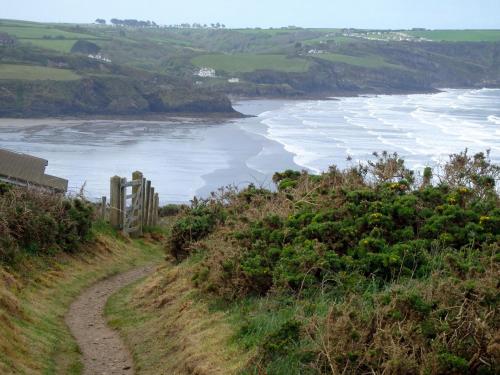 a dirt road next to a beach with waves at Rockfield Broad Haven in Broad Haven