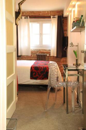 a bedroom with a bed and a table and a chair at Hôtel des Arts in Toulouse