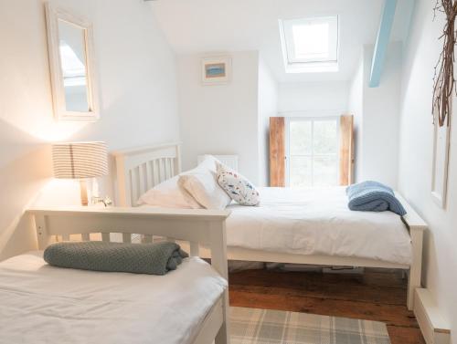 two beds in a room with two windows at Driftwood Cottage Llangrannog in Llangranog