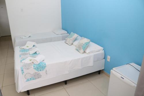 un letto bianco con cuscini e asciugamani di Pousada Lisamar a Mangaratiba
