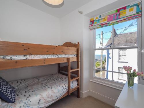 a bedroom with a bunk bed and a window at Brodawel New Quay in New Quay