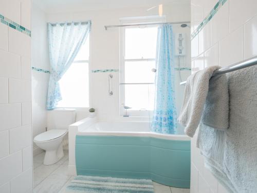 baño con bañera, aseo y ventana en Clydfan Apartment Aberporth, en Aberporth