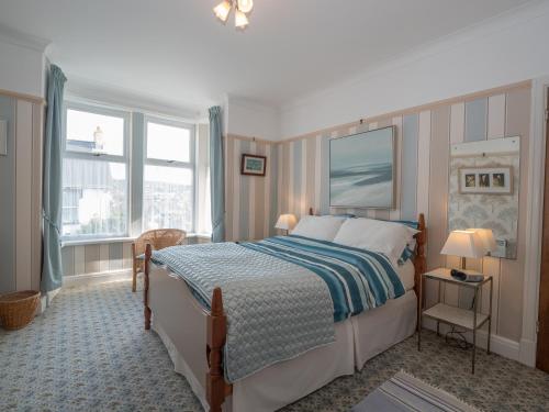 a bedroom with a bed and two windows at Clydfan Apartment Aberporth in Aberporth
