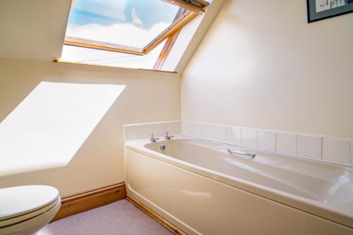 uma casa de banho com um WC, uma banheira e uma janela. em Y Bwthyn St Nicholas em Saint Nicholas