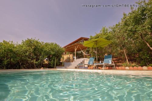 uma piscina com duas cadeiras e um guarda-sol em Utopia Casas Boutique em Oaxaca de Juárez