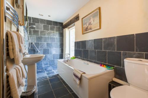 a bathroom with a tub and a sink and a toilet at The Grain Store Newgale in Llandeloy