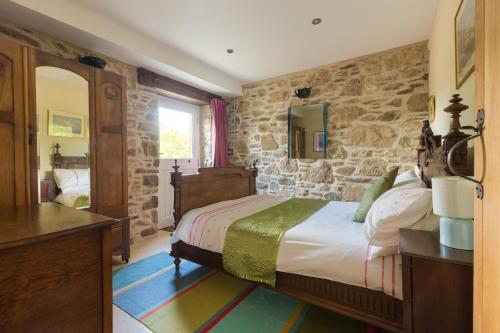 a bedroom with a bed and a stone wall at The Grain Store Newgale in Llandeloy