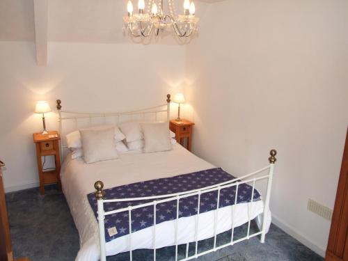 ein Schlafzimmer mit einem weißen Bett mit Kissen und einem Kronleuchter in der Unterkunft Manchester House Narberth in Lampeter-Velfrey