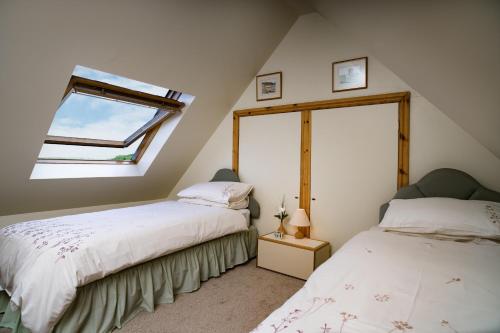 two beds in a attic bedroom with a window at Cnwc Y Bran St Nicholas in Saint Nicholas