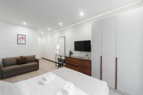 ein Schlafzimmer mit einem Bett, einem Sofa und einem TV in der Unterkunft Select Hotel in Lwiw