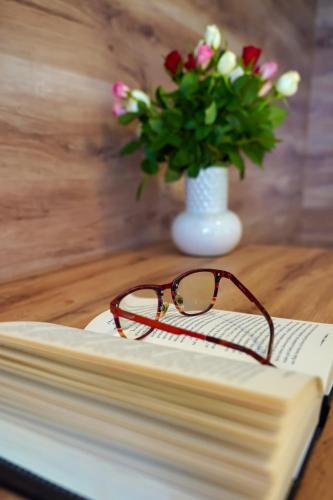 a pair of glasses sitting on a book with a vase of flowers at Hotel Raj in Dedinky