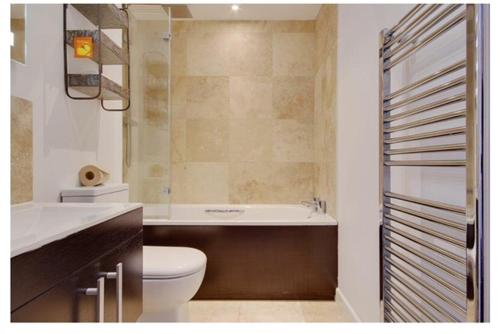 a bathroom with a toilet and a tub and a sink at Beach Penthouse Apartment Bournemouth in Bournemouth