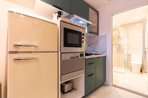 une cuisine avec un réfrigérateur et un micro-ondes dans l'établissement Charmant T3 Neuf - Centre ville Décoration moderne, à Montpellier