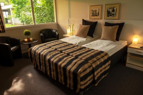 1 dormitorio con 1 cama grande con manta a rayas en Hotel Pejsegaarden, en Brædstrup
