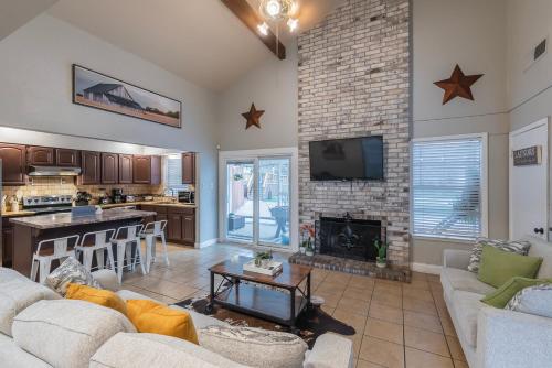 a living room with a fireplace and a kitchen at Pool, Gameroom & Minigolf Enchanting Texas Home in San Antonio