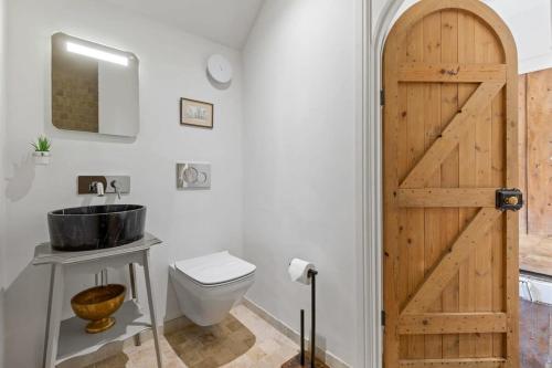 a bathroom with a wooden door and a toilet at North End House - Batheaston in Bath