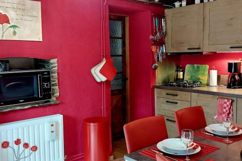 une cuisine aux murs rouges et une table avec des chaises rouges dans l'établissement L'Ardoisière: jolie maison ardennaise., à Alle