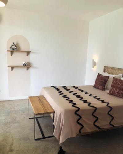 a bedroom with a large bed and a wooden table at Kawga Hôtel in Ngaring