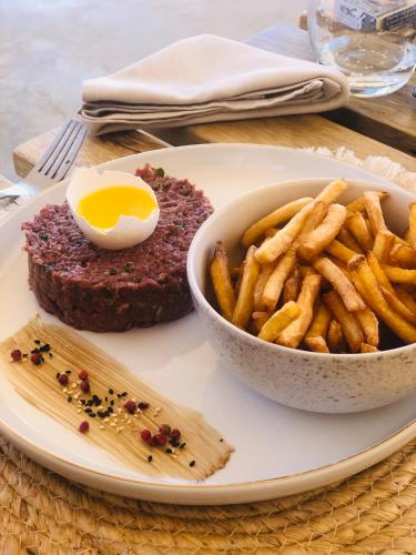 a plate of food with a steak and french fries at Kawga Hôtel in Ngaring