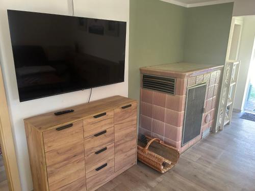 a large flat screen tv on a wall with a wooden dresser at Ferienhaus Fjola in Schenkendöbern