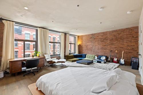 1 dormitorio con 1 cama grande y pared de ladrillo en Tribeca Loft Vanderbilt by RoveTravel, en Nueva York