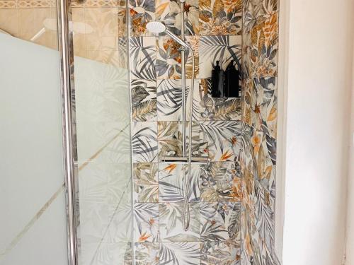 una ducha con una puerta de cristal con mosaicos en MareSole Apartment, en Lido di Ostia