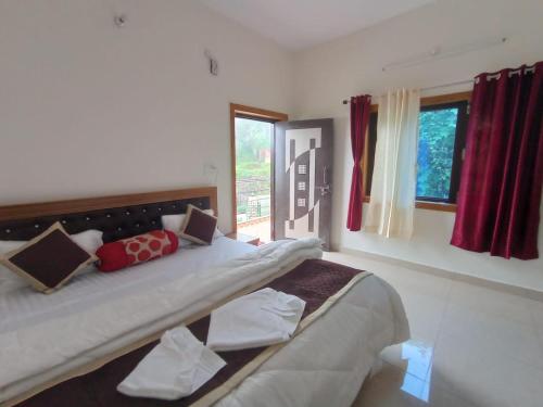 a bedroom with a large bed with red curtains at Sadhna Holiday Home in Bhowāli