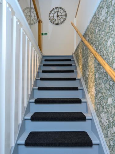 a stairway with blue steps and a clock on the wall at Old Town Loft in Cupar