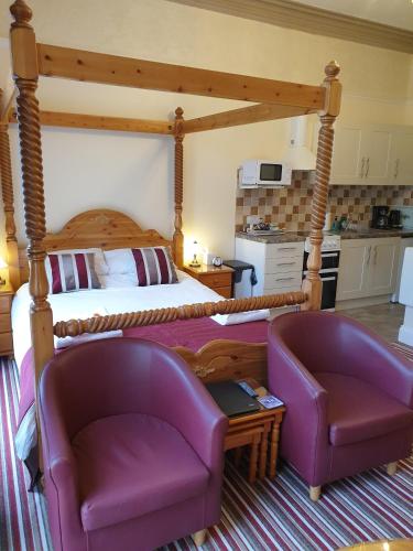 a bedroom with a canopy bed and two chairs at Appletorre House Holiday Flats - Pet Friendly by arrangement and Private Parking in Torquay